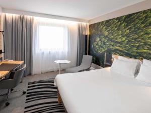 a hotel room with a bed and a painting on the wall at Novotel Marne-la-Vallée Noisy-le-Grand in Noisy-le-Grand