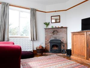 a living room with a fireplace and a red couch at 3 Bed in Dymchurch 46913 in Littlestone-on-Sea