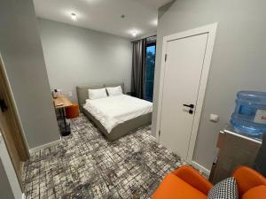 a small bedroom with a bed and an orange chair at Unit Hotel in Almaty +7 photos