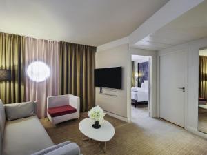 a living room with a couch and a tv at Mercure Paris La Défense in Courbevoie