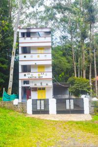 Un edificio blanco con una puerta amarilla delante. en Kavitha nest, en Yercaud
