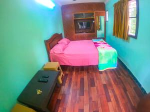 1 dormitorio con 1 cama con sábanas rosas y suelo de madera en Kavitha nest, en Yercaud