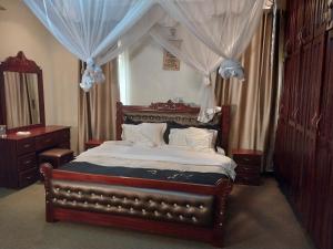 Un dormitorio con una cama grande con dosel. en Villa Grace - Namugongo Road, en Kampala