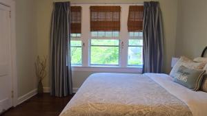 a bedroom with a bed and two windows at The Red Rooster Bungalow in Asheville