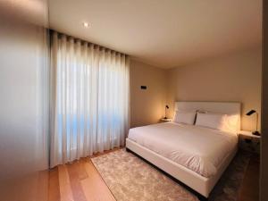 una camera da letto con un letto bianco e una grande finestra di Granja Premium House ad Aveiro