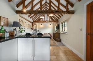 a kitchen with white cabinets and a ceiling with beams at The Potting Shed in Hartfield