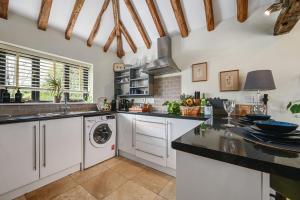 a kitchen with white cabinets and a dishwasher at The Potting Shed in Hartfield