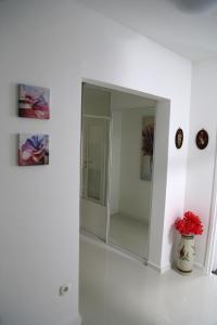 une armoire en verre dans une pièce blanche avec un vase orné de fleurs rouges dans l'établissement Joop Apartment, à Zagreb