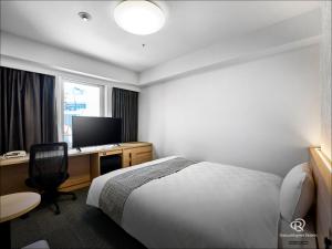 a hotel room with a bed and a desk with a television at Daiwa Roynet Hotel Hamamatsu in Hamamatsu +32 photos