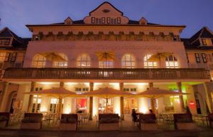 a building with tables and umbrellas in front of it at Mintrops Stadt Hotel Margarethenhöhe in Essen