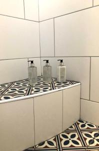 a bathroom with three soap bottles on a counter at Essio's Garden Apartment, Simons Town South Africa in Simonʼs Town