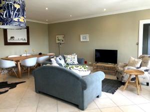 a living room with a blue couch and a table at Essio's Garden Apartment, Simons Town South Africa in Simonʼs Town