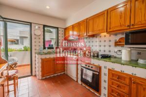 a kitchen with wooden cabinets and a stove top oven at Villa independiente con acceso a la playa in Son Xoriguer