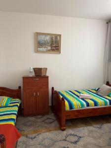 a bedroom with two beds and a cabinet and a picture at 2- izbový APARTMÁN KAJKA v PENZION TRSTENÁ in Trstená