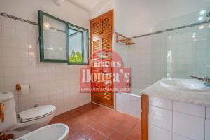 a bathroom with a toilet and a sink and a mirror at Villa independiente con acceso a la playa in Son Xoriguer +10 photos