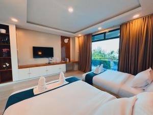 a hotel room with two beds and a television at De Cairo's Mountain & Ocean View Resort 