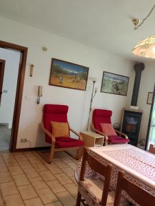 a living room with two red chairs and a fireplace at Piera' s House in Caderzone