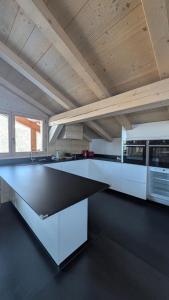una cucina con mobili bianchi e un piano di lavoro nero di Le Chalet MontBlanc a Bionnay
