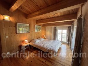een slaapkamer met een bed in een kamer met houten wanden bij La Villa de la Clairiere in Le Bois-Plage-en-Ré