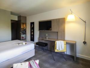 a hotel room with a bed and a desk at Novotel Nantes Centre Gare in Nantes
