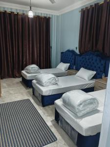 three beds in a room with blue walls and curtains at بسمة الدهاريز Basmat Aldahariz in Salalah