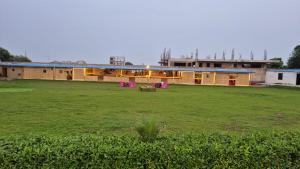 un edificio con un campo verde delante de él en Padharo Sa Bikaner Wale, en Vrindāvan