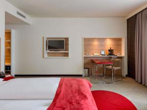 a bedroom with a bed and a desk and a television at Mercure Hotel Stuttgart Airport Messe in Stuttgart