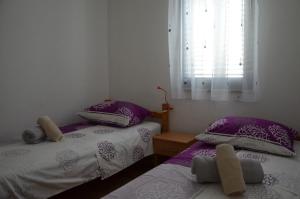 two beds in a room with purple pillows and a window at Apartment Drazan in Šibenik