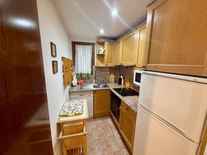 a kitchen with wooden cabinets and a white refrigerator at C19 - Bellavista Pirineo - Villmor in Cerler +7 photos