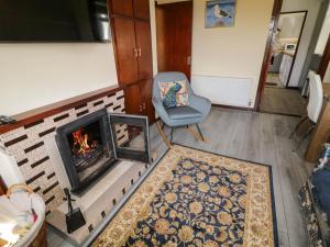 Una sala de estar con una silla y una chimenea. en Loch Illion View, en Meenmore
