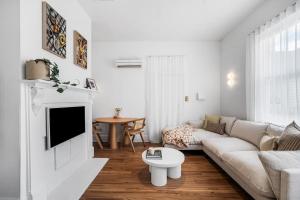 a white living room with a couch and a table at The Piccolo Cottage in Hobart