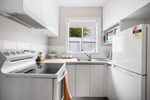 a white kitchen with a sink and a refrigerator at The Piccolo Cottage in Hobart