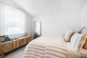 a white bedroom with a bed and a window at The Piccolo Cottage in Hobart