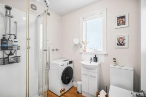 a white bathroom with a washing machine and a sink at The Piccolo Cottage in Hobart +28 photos