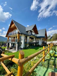 a house with a wooden fence in front of it at Apartamenty Butorowy in Kościelisko