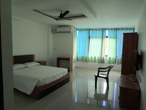 Un dormitorio con una cama y una silla y una ventana. en Hotel O Erumeli Bus Terminal Kottayam Formerly Pious B Residency, en Erumeli