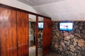 a room with a stone wall with a television on it at Ferienwohnung echt kanarisch mit Meer und Teide Blick La Vega Teneriffa Nord in Icod de los Vinos
