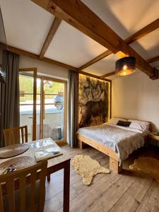 a bedroom with a bed and a table and a window at Apartamenty Butorowy in Kościelisko