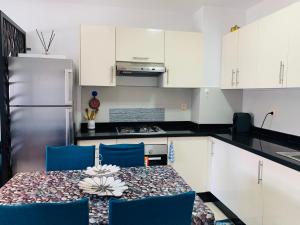 a kitchen with a table with blue chairs and white cabinets at Sunset Eden sea view in Aourir