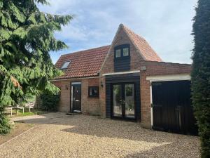 ein Backsteinhaus mit einer Garage und einer Auffahrt in der Unterkunft The Stables, a delightful 3 bed house near the Norfolk Broads in Upton