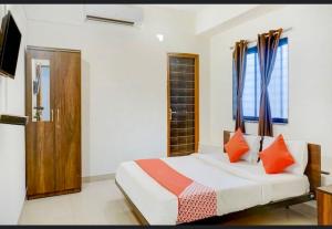 a bedroom with a bed with orange pillows at Super Hotel O Sai inn 2 in Pune