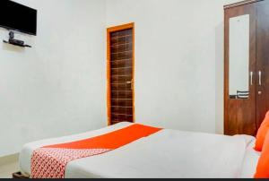 a bedroom with a bed with an orange blanket at Super Hotel O Sai inn 2 in Pune