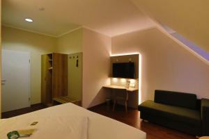 a room with a bed and a couch and a table at Weinhotel Wasem in Ingelheim am Rhein
