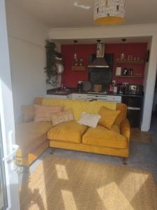 a yellow couch in a living room with a kitchen at Halwyn Retreat in St Austell