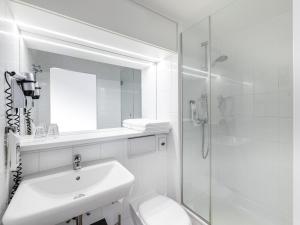 a white bathroom with a sink and a shower at ibis Hotel Frankfurt Messe West in Frankfurt/Main