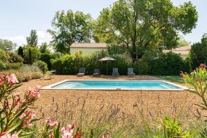 MoulèsMaison en campagne Arlésienne avec piscine的院子里有游泳池，有椅子和树木