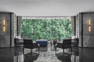 eine Lobby mit Stühlen und einem großen Fenster mit Bäumen in der Unterkunft Lavande Hotel Guangzhou Beijing Road Pedestrian Street Haizhu Square Metro Station Branch - Free Deliver Service to Canton Fair Complex During Canton Fair Period in Guangzhou
