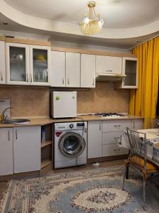 a kitchen with white cabinets and a washing machine at Центр города Цум in Almaty