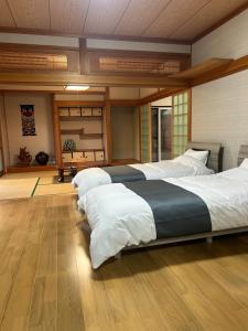 1 dormitorio con 2 camas grandes con sábanas blancas en アットホーム五島, en Goto