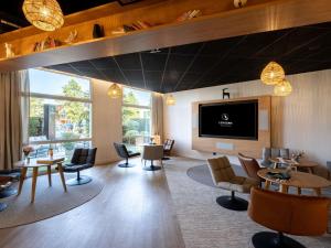 a waiting room with tables and chairs and a flat screen tv at Mercure Compiègne Sud in Compiègne